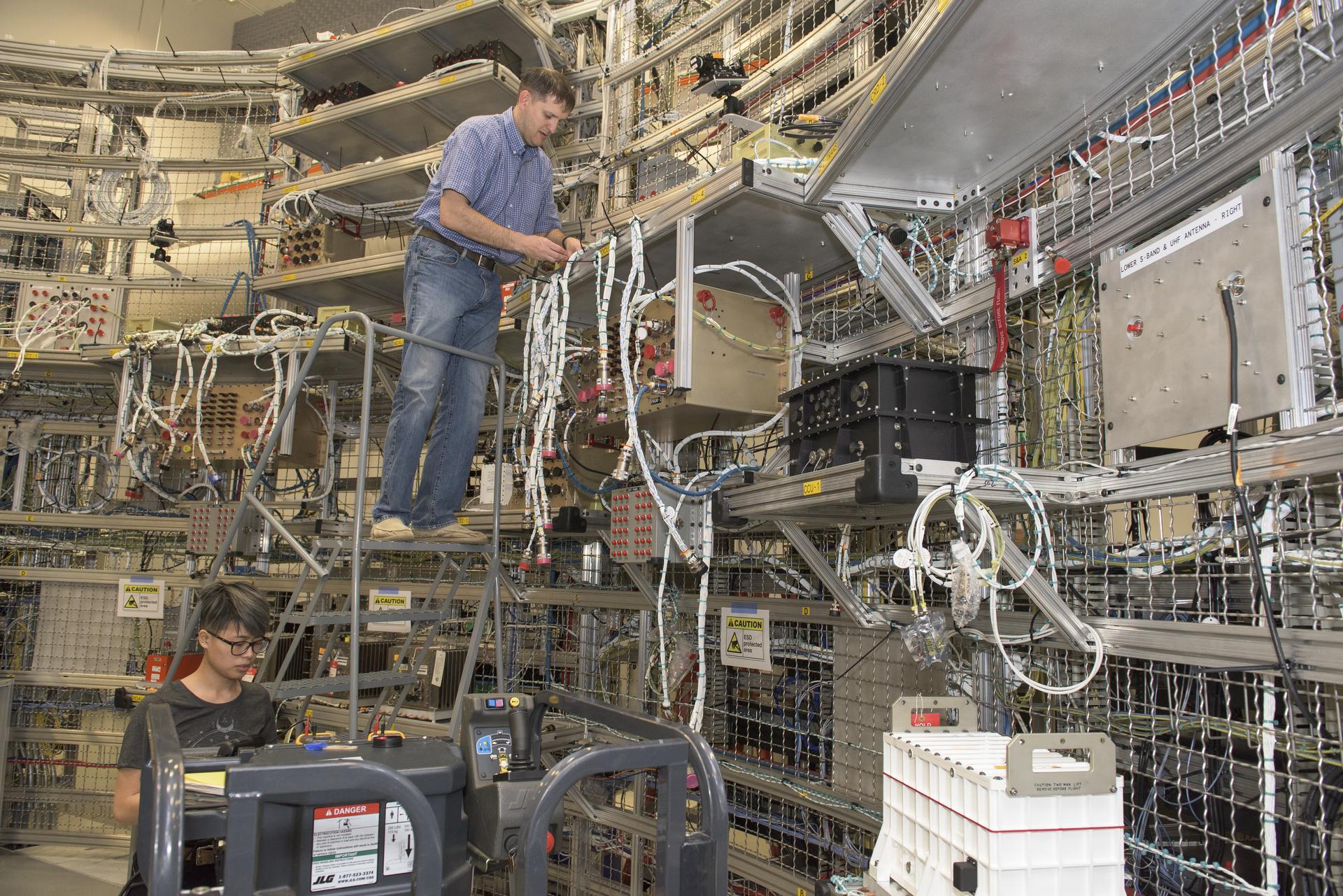 Engineers inspecting avionics cables at a systems integration test facility