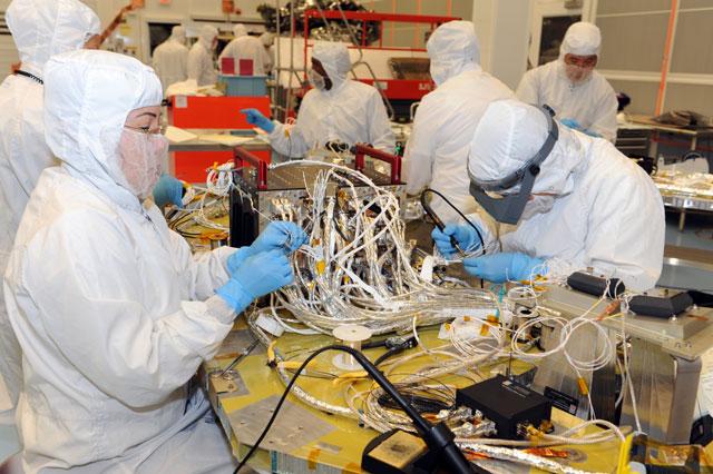 Electrical technicians building command and data handling connector harnessing